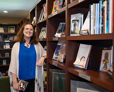 Emily Hizny stands in front of a bookcase.